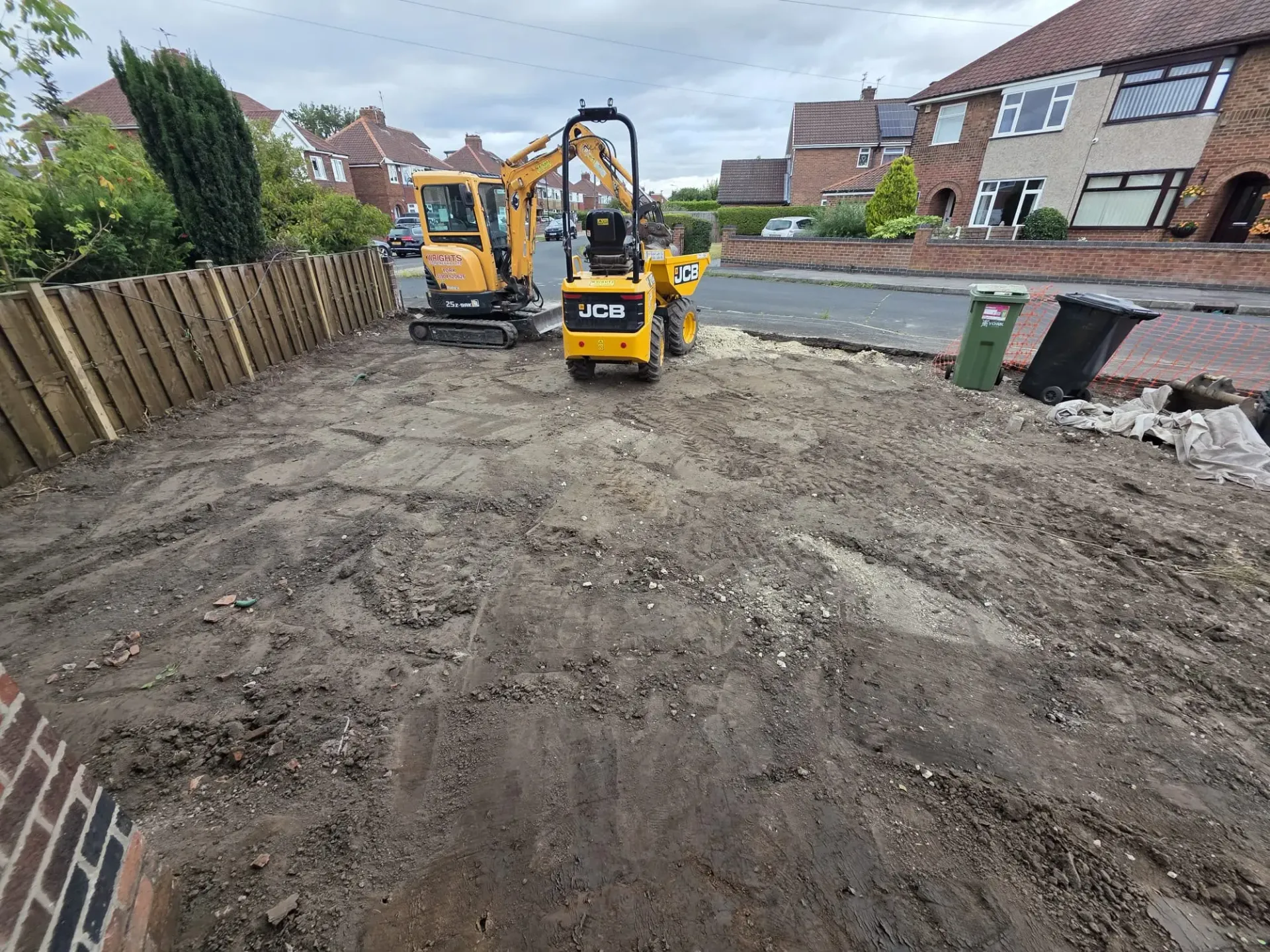 Mini excavator and JCB dumper carrying out groundwork and driveway preparation in a residential area in York