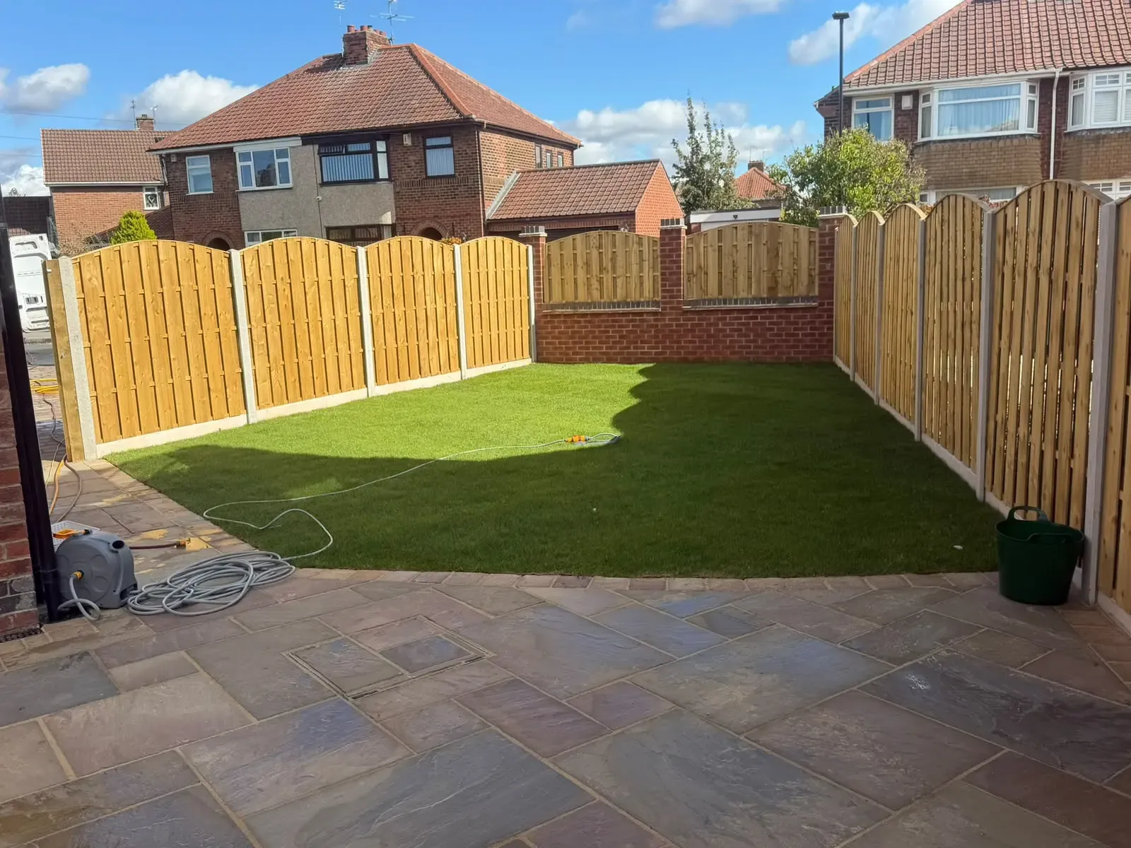 Newly laid natural stone patio and lawn installation with integrated recessed drainage manhole cover in York