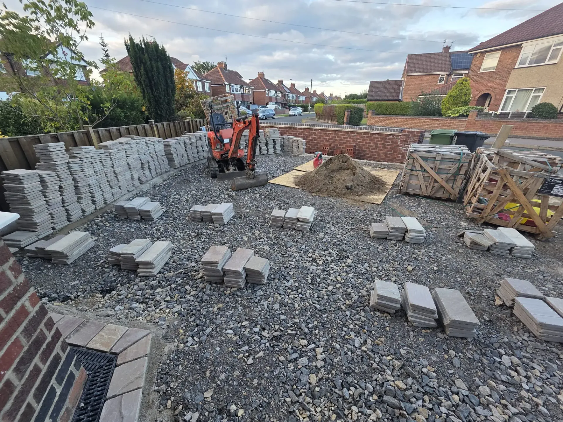 Driveway and patio groundwork preparation with paving slabs, mini digger, and channel drainage installation in York